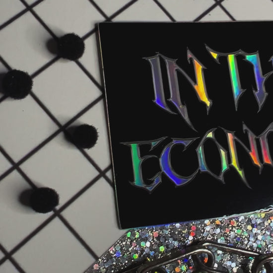 Holographic Metal font sticker with black background that says In this economy